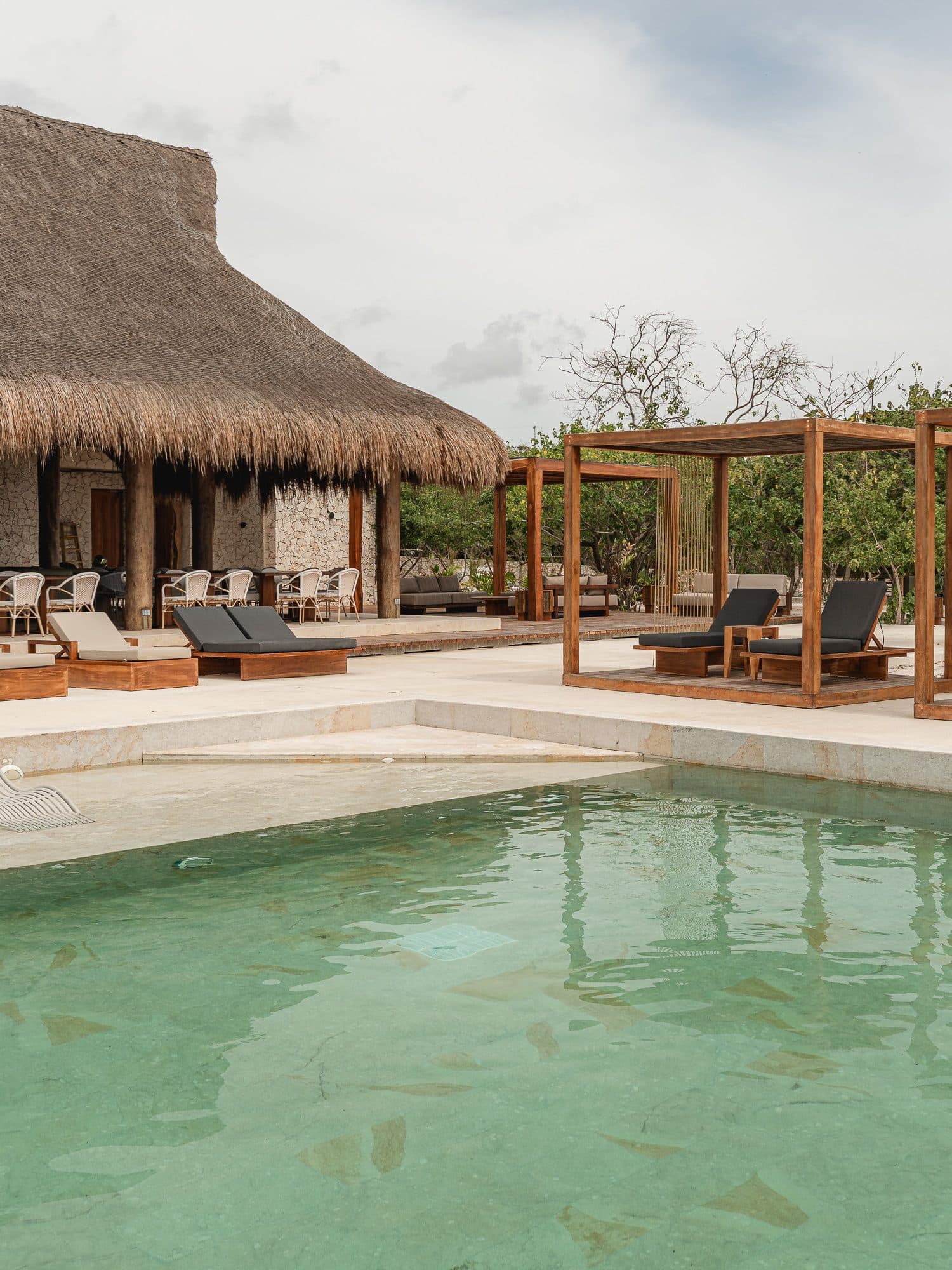 Piscina de hotel con camastros y pérgolas en madera