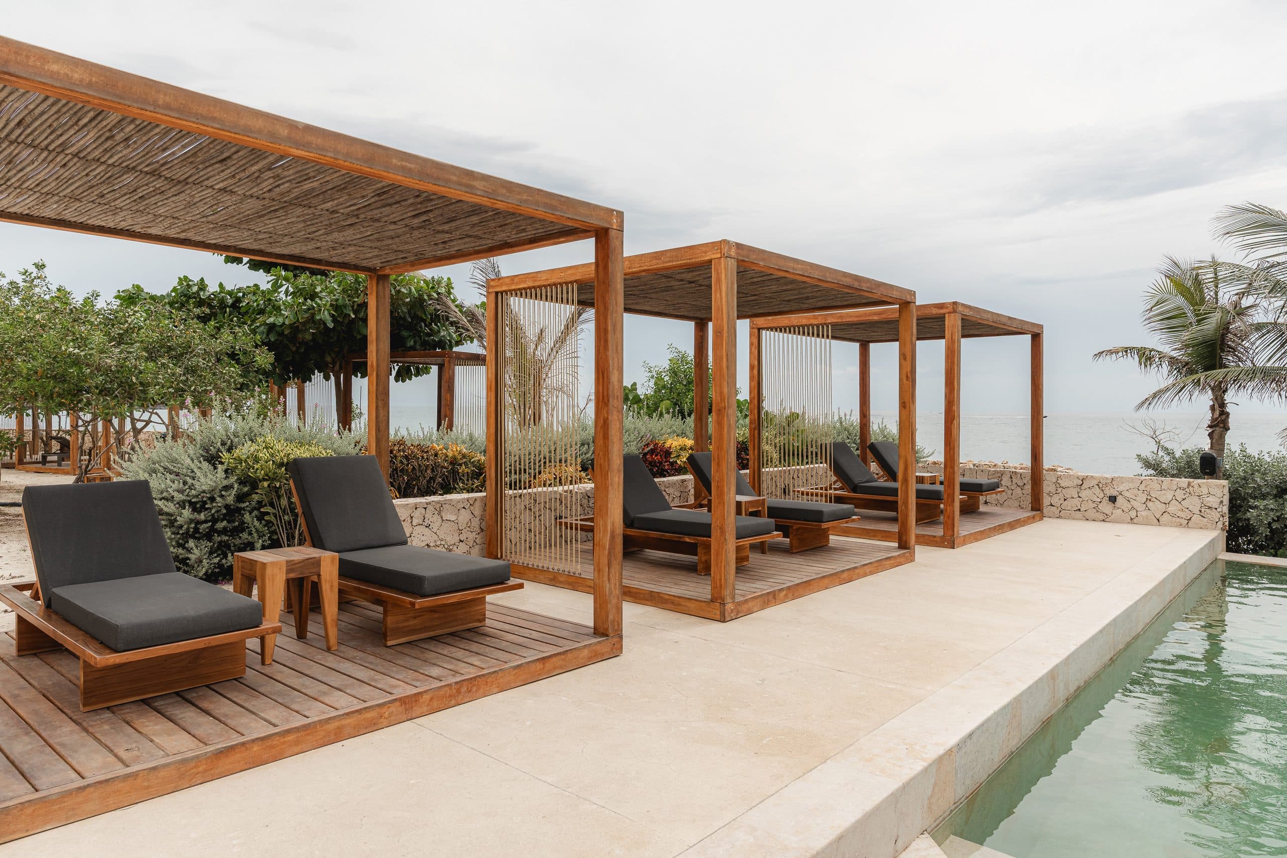Pérgolas y camastros en madera fabricados por Mowle frente a la piscina del proyecto Lazuli